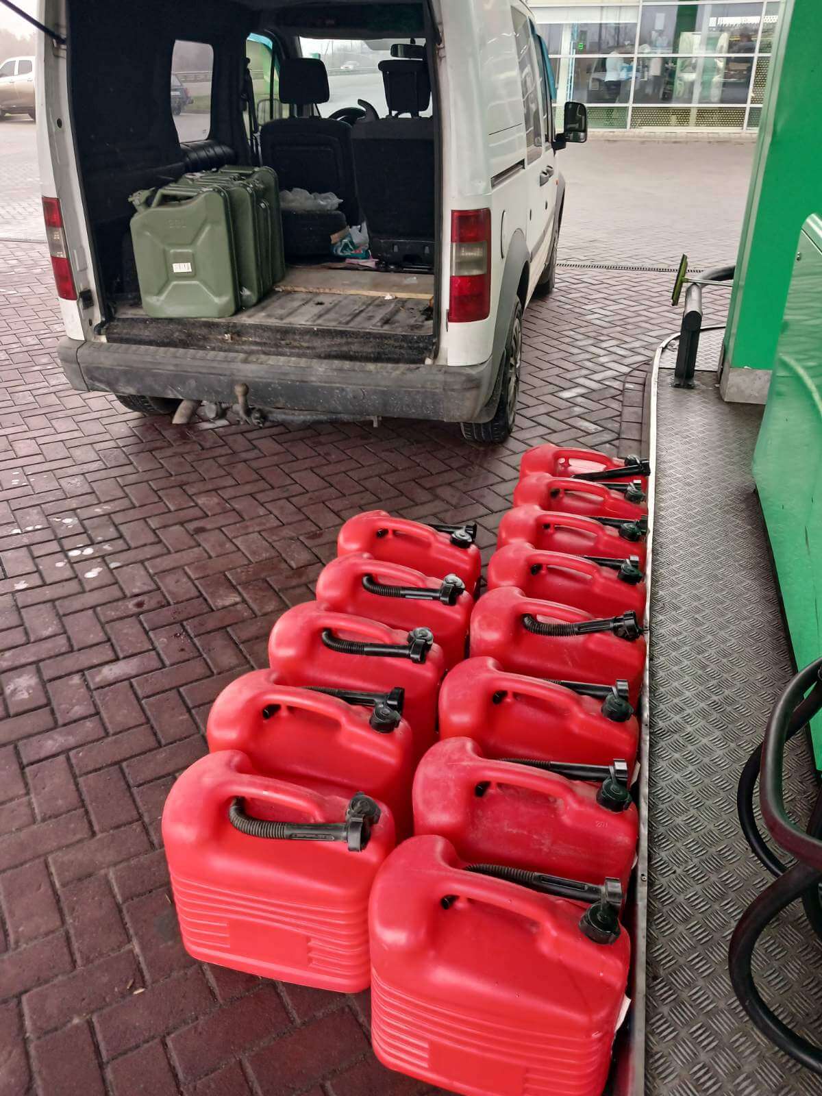 De jerrycans worden gevuld met benzine 